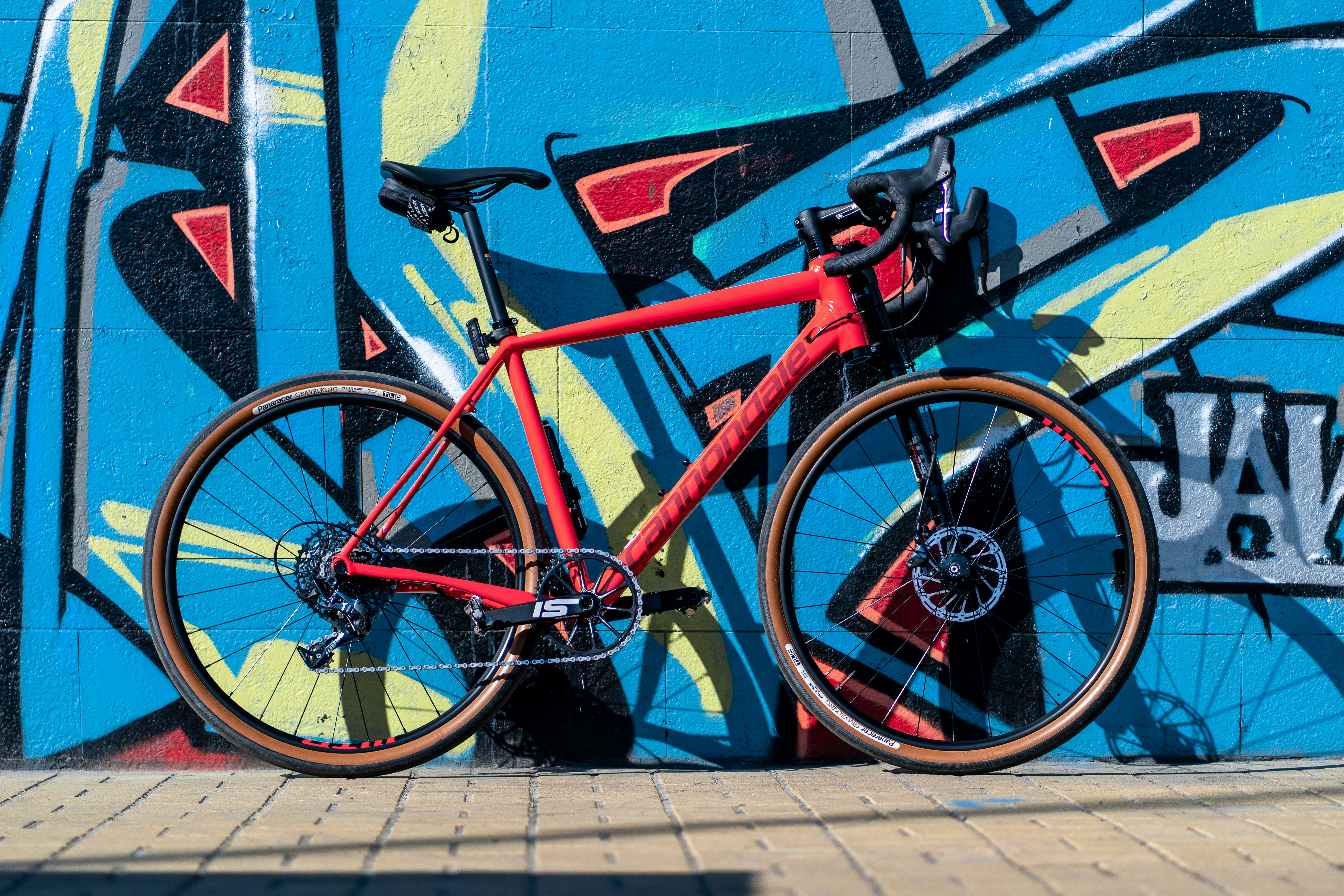 red and black road bike parked beside blue wall